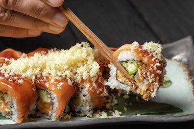 Erkeklerin ellerinde yemek çubuklarını kapat. Lokantada porsiyon suşi al. Yemek çubukları kullanarak suşi ye.