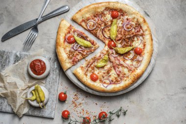 Jambonlu lezzetli pizza, mozzarella, mermer tepside kıyma. Gri taşlı arka planda pizza malzemeleriyle süslenmiş. 