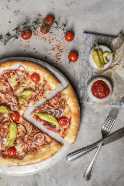 Jambonlu lezzetli pizza, mozzarella, mermer tepside kıyma. Gri taşlı arka planda pizza malzemeleriyle süslenmiş. 