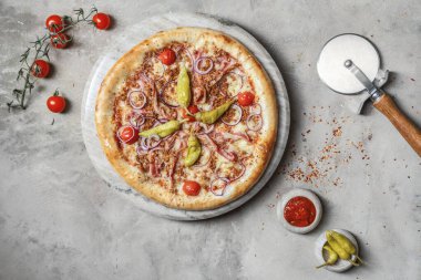 Jambonlu lezzetli pizza, mozzarella, mermer tepside kıyma. Gri taşlı arka planda pizza malzemeleriyle süslenmiş. 