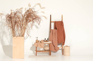 Doğal waffle keten havluları ahşap bankta toprak tonları ve bambu diş fırçaları, rattan sepetleri ve sabun makinesiyle havlu merdiveni. Günlük vücut bakımı, spa ve sıhhat sıfır atık tuvalet kavramı 