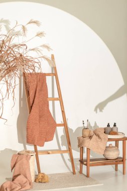 Doğal waffle keten havluları ahşap bankta toprak tonları ve bambu diş fırçaları, rattan sepetleri ve sabun makinesiyle havlu merdiveni. Günlük vücut bakımı, spa ve sıhhat sıfır atık tuvalet kavramı 