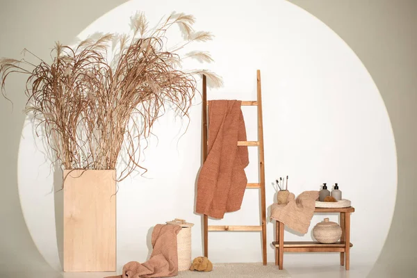 Natural waffle linen towels in earth tones on wood bench and towel ladder with bamboo toothbrushes, rattan baskets, and soap dispenser. Daily body care, spa and wellness zero waste bathroom concept