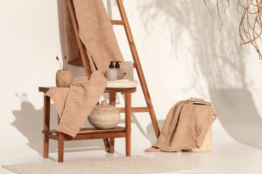 Doğal waffle keten havluları ahşap bankta toprak tonları ve bambu diş fırçaları, rattan sepetleri ve sabun makinesiyle havlu merdiveni. Günlük vücut bakımı, spa ve sıhhat sıfır atık tuvalet kavramı 