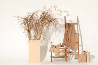 Doğal waffle keten havluları ahşap bankta toprak tonları ve bambu diş fırçaları, rattan sepetleri ve sabun makinesiyle havlu merdiveni. Günlük vücut bakımı, spa ve sıhhat sıfır atık tuvalet kavramı 