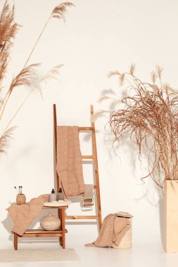 Doğal waffle keten havluları ahşap bankta toprak tonları ve bambu diş fırçaları, rattan sepetleri ve sabun makinesiyle havlu merdiveni. Günlük vücut bakımı, spa ve sıhhat sıfır atık tuvalet kavramı 