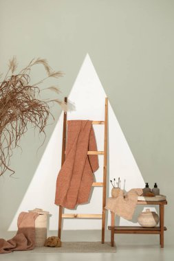 Doğal waffle keten havluları ahşap bankta toprak tonları ve bambu diş fırçaları, rattan sepetleri ve sabun makinesiyle havlu merdiveni. Günlük vücut bakımı, spa ve sıhhat sıfır atık tuvalet kavramı 