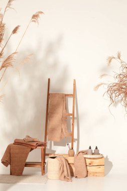 Doğal waffle keten havluları ahşap bankta toprak tonları ve bambu diş fırçaları, rattan sepetleri ve sabun makinesiyle havlu merdiveni. Günlük vücut bakımı, spa ve sıhhat sıfır atık tuvalet kavramı 