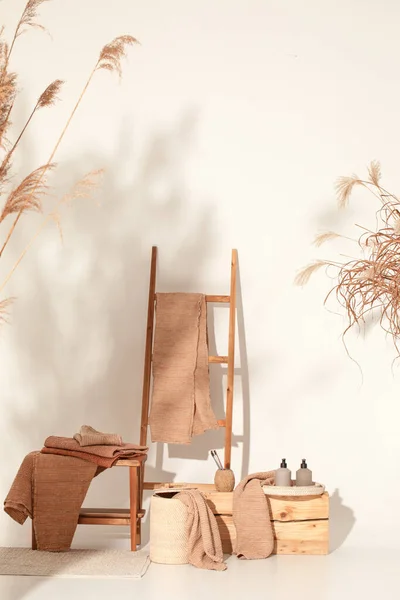 Doğal waffle keten havluları ahşap bankta toprak tonları ve bambu diş fırçaları, rattan sepetleri ve sabun makinesiyle havlu merdiveni. Günlük vücut bakımı, spa ve sıhhat sıfır atık tuvalet kavramı 