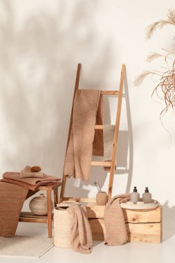 Doğal waffle keten havluları ahşap bankta toprak tonları ve bambu diş fırçaları, rattan sepetleri ve sabun makinesiyle havlu merdiveni. Günlük vücut bakımı, spa ve sıhhat sıfır atık tuvalet kavramı 