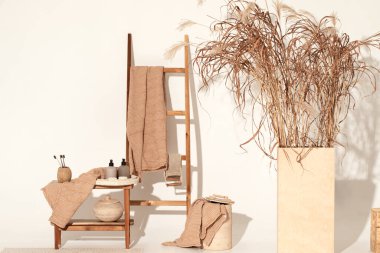 Doğal waffle keten havluları ahşap bankta toprak tonları ve bambu diş fırçaları, rattan sepetleri ve sabun makinesiyle havlu merdiveni. Günlük vücut bakımı, spa ve sıhhat sıfır atık tuvalet kavramı 