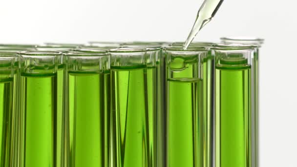 Aggiunta di gocce di liquido in una provetta riempita di liquido verde — Video Stock