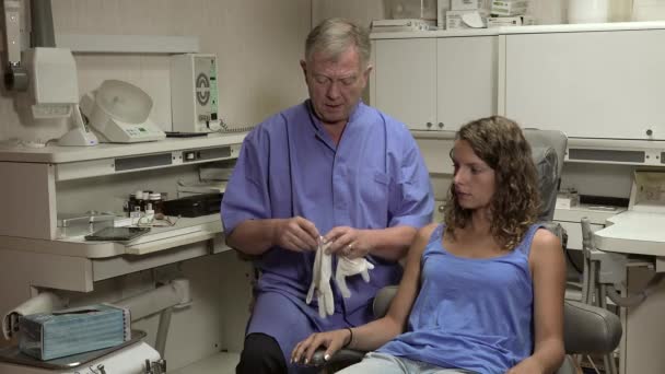 Zahnarzt zieht Handschuhe in der Nähe seiner Patientin an — Stockvideo