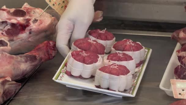 De slager bestanden haar producten in een gekoelde vitrine — Stockvideo