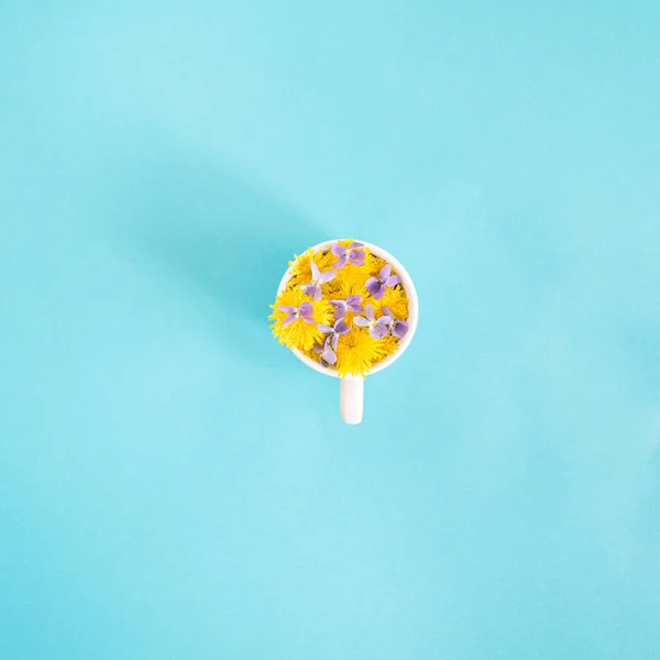 cup of coffee with sunny spring flowers.yellow on a blue background.minimal concept