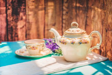 Gün batımında bir fincan çay ve güzel bir porselen çaydanlık.