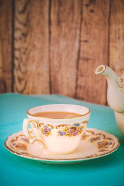 Gün batımında bir fincan çay ve güzel bir porselen çaydanlık.