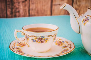 Gün batımında bir fincan çay ve güzel bir porselen çaydanlık.