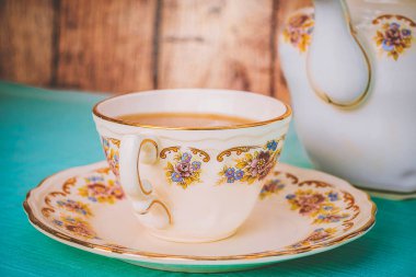 Gün batımında bir fincan çay ve güzel bir porselen çaydanlık.