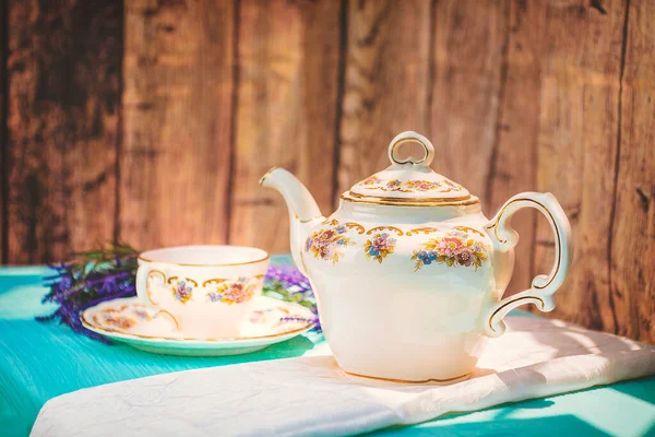 View of a cup of tea and a fine china teapot on a table at sunset