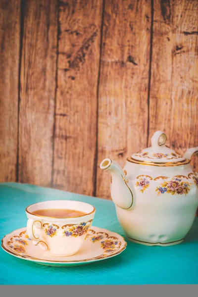 View of a cup of tea and a fine china teapot on a table at sunset