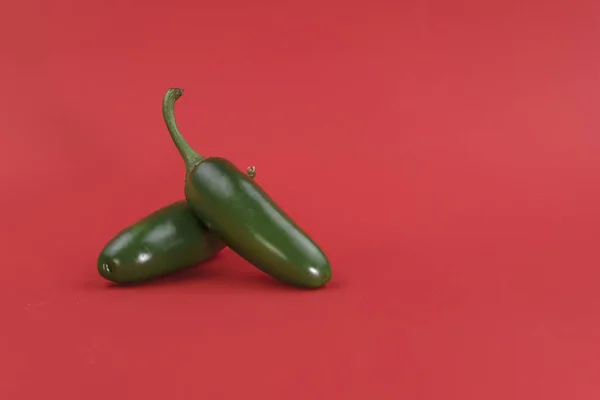 成熟的绿色辣椒在红色背景 背景有空间添加文字 图库照片