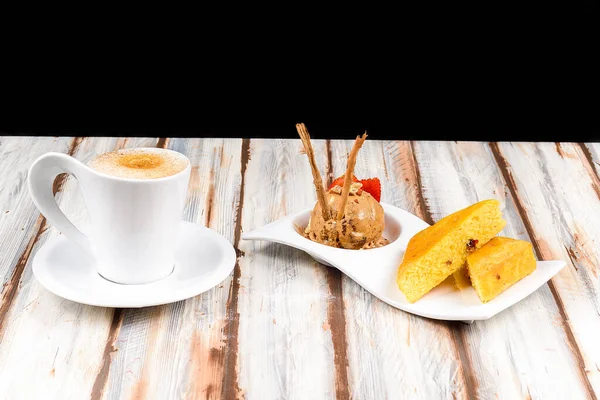 On the table of a restaurant there is a foreground a vanilla oanque with a chocolate and cinnamon ice cream and a cup of coffee