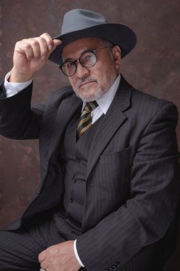 Koyu kahverengi çizgili ve şapkalı bir beyefendi kameraya poz veriyor.