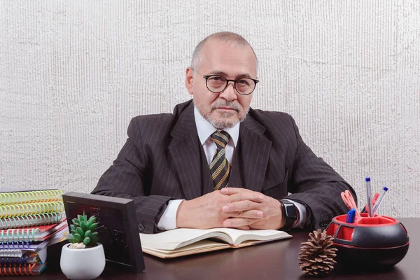 Masasında oturmuş not alan bir öğretmene yakın çekim.