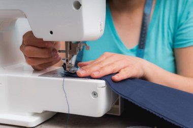 Moda atölyesinde çalışırken dikiş diken neşeli bir kadın.