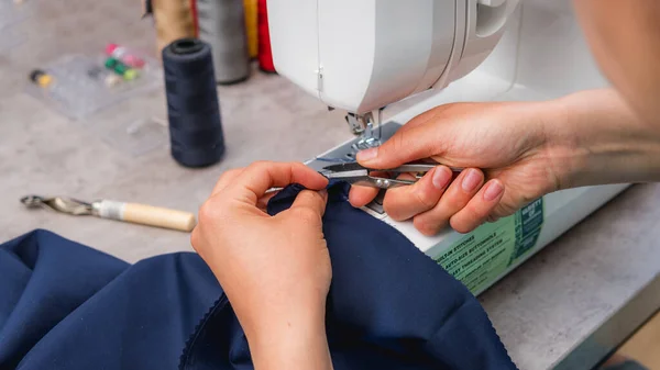 Moda atölyesinde çalışırken dikiş diken neşeli bir kadın.