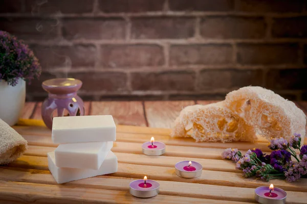 Doğal sabunların, kokulu mumların ve banyo aksesuarlarının bulunduğu güzel bir spa kompozisyonu. Arınma konsepti için romantik bir ortam. Sığ alan derinliği ve metin için yer var.