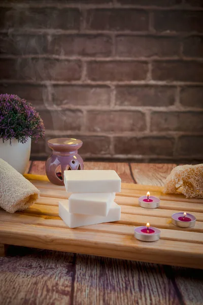 Beautiful spa composition with natural soaps with scented candles and bathroom accessories in a romantic setting for a cleansing concept. There is shallow depth of field and room for text.