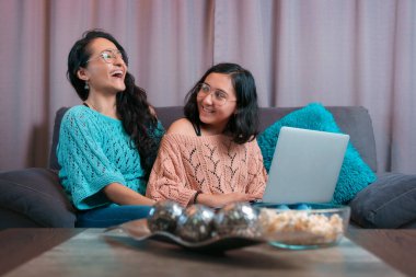 Anne ve kızının dizüstü bilgisayar kullanışının yatay görüntüsü anne bilgisayarda gördüğü bir şeye gülüyor ve kızı annesinin ne yaptığını görmek için dönüyor.