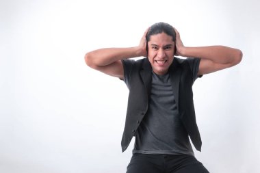 Beyaz arka planı olan bir adam, jest yapan bir adam, kulaklarını kapatır çünkü çok fazla gürültü vardır, çevredeki gürültüden rahatsız olur.