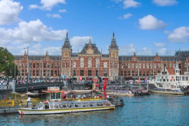 20 Ağustos 2025, Amsterdam, Hollanda. Sıcak bir yaz gününde arka planda Amsterdam Merkez İstasyonu ile sokaklarda yürüyorum..