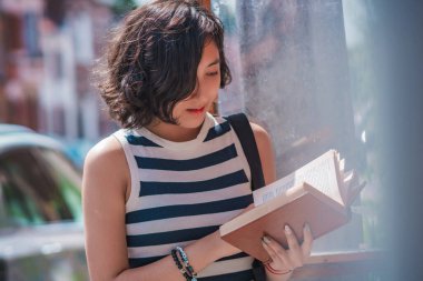 Genç bayan, sokaktaki bir kutu kitaptan bir kitap alın, kaldırımda duruyor, bu kutular Avrupa ülkelerinde tipik olarak sakinleri arasında okumayı teşvik eden kitaplar..