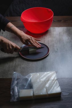 Evde, doğal banyo sabunu yapmak için organik sabun macunu kesen bir kadının ellerini görebilirsiniz. Ev yapımı. Yüzde yüz doğal..