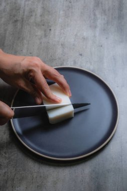 Evde, doğal banyo sabunu yapmak için organik sabun macunu kesen bir kadının ellerini görebilirsiniz. Ev yapımı. Yüzde yüz doğal..