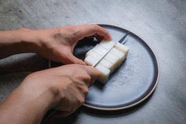 Evde, doğal banyo sabunu yapmak için organik sabun macunu kesen bir kadının ellerini görebilirsiniz. Ev yapımı. Yüzde yüz doğal..