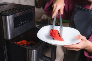 Evdeki hazırlık. Mutfakta bir kadın tavukları kızartmak için fırına koyuyor..