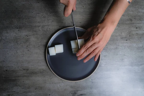 Evde, doğal banyo sabunu yapmak için organik sabun macunu kesen bir kadının ellerini görebilirsiniz. Ev yapımı. Yüzde yüz doğal..