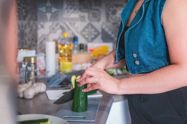 Mutfağında bir kadın mutfak bıçağıyla kabak kesiyor. Ev yapımı yemek hazırlama.