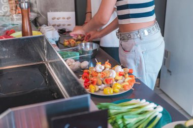Kırmızı biber, mantar ve düğmeli mantar şiş; kadın öğle yemeği için şiş hazırlıyor. Ev yapımı gıda konsepti.