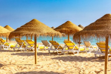 Albufeira plajı, Algarve, Portekiz 'deki şezlongları ve şezlongları yakından izleyin. Mavi gökyüzü ve altın kum.