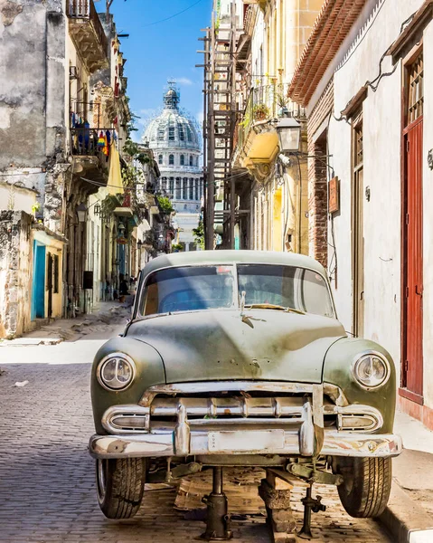 Eski araba, Capitolio 'nun arka planında eski Havana sokaklarında tamir ediliyor.