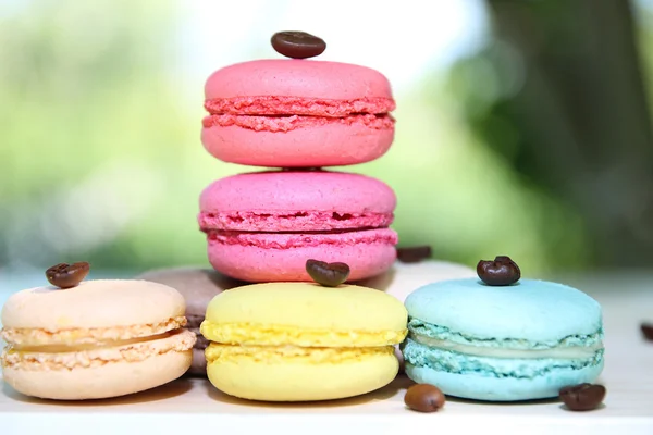 Colorful french macaroons with coffee on the nature background