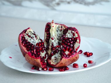 Beyaz bir masada, bir tabakta nar. Nar kesimi