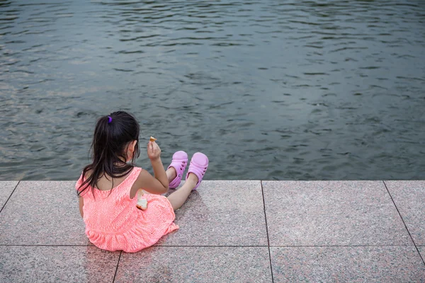 Το παιδί κάθεται και σίτιση τα ψάρια στη λίμνη — Φωτογραφία Αρχείου