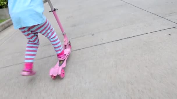 Chica montando scooter rosa en la calle: Tracking Shot — Vídeo de stock